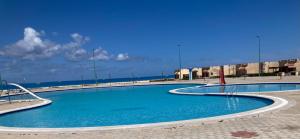 a swimming pool on the beach with the ocean in the background at Maison sur plage in Al Ḩammām