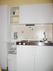a kitchen with white cabinets and a sink at Pension Arndt UG in Wangerland +55 photos
