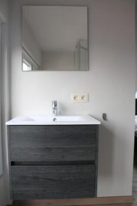La salle de bains est pourvue d'un lavabo et d'un miroir. dans l'établissement Momaison charmant landelijk appartement, à Knesselare