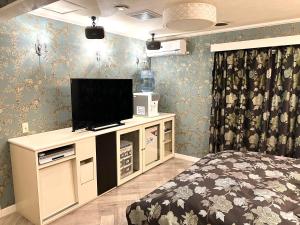 a bedroom with a bed and a television on a cabinet at ホテル 夢街道 