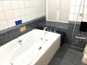 eine weiße Badewanne im Bad mit Spiegel in der Unterkunft ホテル 夢街道 