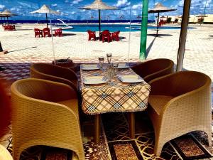 einen Tisch am Strand mit Tisch und Stühlen in der Unterkunft Maison sur plage in Al Ḩammām