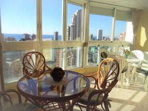a glass table and chairs in a room with a window at Ola Azul Sea View Apartment in Benidorm