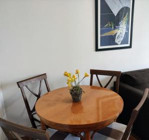 uma mesa de madeira com um vaso com flores amarelas em Apartamentos Sanxenxo Progreso 140 em Sanxenxo