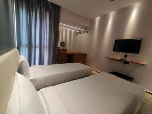 Habitación de hotel con 2 camas y TV de pantalla plana. en TERRACE BUSINESS HOTEL KOZHIKODE en Kozhikode