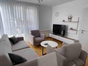 een woonkamer met een bank en stoelen en een tv bij Arian's Apartment in Pristina