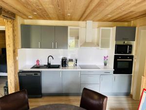 a kitchen with white cabinets and black appliances at ※ Résidence POMME DE PIN - Terrasse - Nature ※ in Xonrupt-Longemer