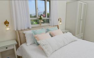 1 dormitorio con cama con almohadas y ventana en סוויטת בוסתן ונחל, en Dafna