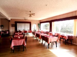 a dining room with red tables and chairs and windows at Altavia Hotel in Sandown