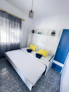 1 cama blanca con almohadas amarillas en una habitación en Coastline Apartment en Néa Péramos