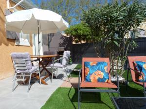 eine Terrasse mit einem Tisch, Stühlen und einem Sonnenschirm in der Unterkunft appart cosy avec son exterieur chaleureux,piscine et parking prive in Fontvieille