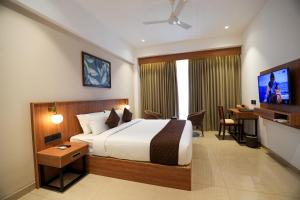 a bedroom with a bed and a desk and a television at Hotel Saffron Wayanad in Sultan Bathery