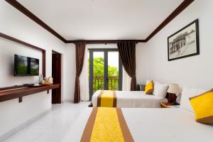 a hotel room with two beds and a tv at Haemer Villa Hoi An in Hoi An