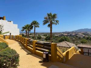 een geel hek met palmbomen op de achtergrond bij Lomas del Mar 5 Magnifique appart -piscine chauffée , paddle, clim, Vue panoramique in Playas de Vera