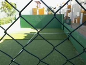 een tennisbaan gezien door een hek met een ketting bij Lomas del Mar 5 Magnifique appart -piscine chauffée , paddle, clim, Vue panoramique in Playas de Vera