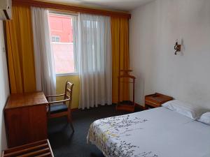 a bedroom with a bed and a desk and a window at Aina Hôtel in Antananarivo