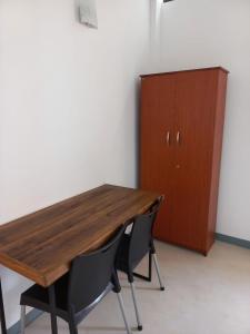 a wooden table and two chairs next to a cabinet at The Anchorage Holiday Apartments - Negombo in Negombo
