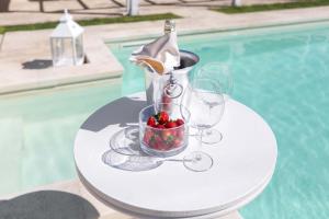 un tavolo con bicchieri da vino, una bottiglia e una ciotola di fragole di Dependance di Omero by BarbarHouse a Cavallino di Lecce