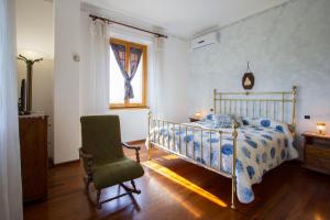 1 dormitorio con 1 cama, 1 silla y 1 ventana en Casa Pupa- Azienda Fontelunga, en Cortona