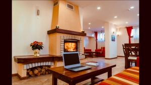 Private Spa Luxury apartments في بانسكو: غرفة معيشة مع موقد وجهاز كمبيوتر محمول على طاولة