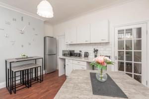 a white kitchen with a vase of flowers on a counter at Leeds 4-Bed House - Sleeps 9 Free Parking & WiFi in Leeds +26 photos