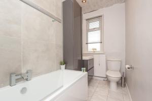 a white bathroom with a tub and a toilet at Leeds 4-Bed House - Sleeps 9 Free Parking & WiFi in Leeds