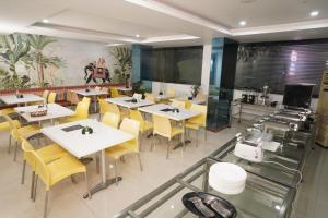 a restaurant with white tables and yellow chairs at Hotel Marigold Atnest Gachibowli - A Business Hotel in Gachibowli