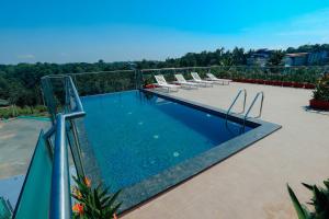 a swimming pool with lounge chairs on a patio at Hotel Saffron Wayanad in Sultan Bathery