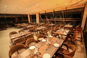 a restaurant with wooden tables and chairs and windows at Hotel Saffron Wayanad in Sultan Bathery