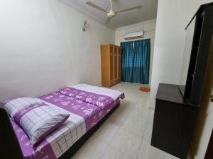 una camera con letto viola e TV a schermo piatto di HELLO HOMESTAY a Nibung Tebal