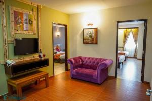 a living room with a purple couch and a tv at Herald Hotel Melaka by D'Concept in Malacca