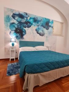 - une chambre dotée d'un lit bleu et d'une peinture murale dans l'établissement Casa Giulia, à LʼAquila