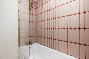 a bathroom with pink tiled walls and a tub at The City of London Secret - Classy 1BDR Flat in London