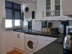 a kitchen with white cabinets and a washing machine at West Park in Hope Cove