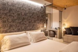 1 dormitorio con cama blanca y sofá en Relais Limonaia - Suites & Garden SPA, en Torri del Benaco