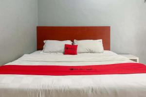 a bed with a red blanket on top of it at RedDoorz at Jalan Sei Batang Hari Medan in Medan