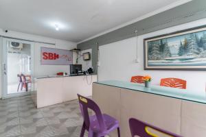 a kitchen with a counter and purple chairs in a room at RedDoorz at Jalan Sei Batang Hari Medan in Medan