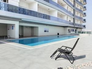 a chair in front of a swimming pool in a building at Key View Hera Tower in Dubai