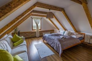 a bedroom with a bed and a couch in a attic at Tagyon Birtok Mandula Apartmanház in Tagyon
