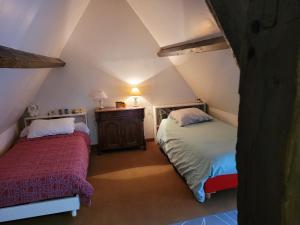 a attic bedroom with two beds and a table at La Porterie face à l'abbaye in Le Bec-Hellouin