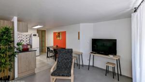 - un salon avec une télévision, une table et des chaises dans l'établissement Suite Fidji, à Luxeuil-les-Bains