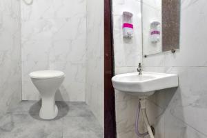 a white bathroom with a sink and a toilet at FabHotel Nidhivan, Udhna Junction in Surat