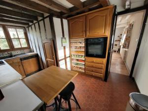 a kitchen with a table and a tv in a room at La Porterie face à l'abbaye in Le Bec-Hellouin