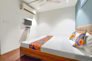a bedroom with a bed and a tv on the wall at FabHotel Nidhivan, Udhna Junction in Surat