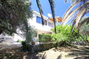 a white house with palm trees in front of it at Apartments Dajana in Orebić