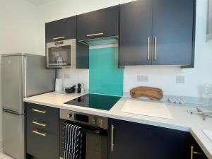 a kitchen with black cabinets and a stove top oven at Top Deck - Fresh, stylish seaside apartment in Ventnor