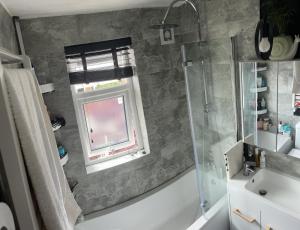 uma casa de banho com um chuveiro, um lavatório e uma janela em Room in family home em Teversham