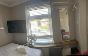 a bedroom with a bed and a window with a fan at Room in family home in Teversham