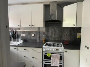 una cucina con armadi bianchi e piano cottura di Room in family home a Teversham