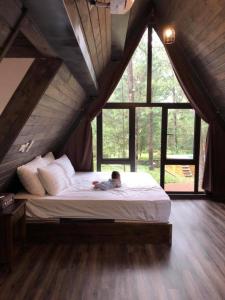 a boy laying on a bed in a room with windows at La Pineta Sóc Sơn - Venuestay in Sóc Sơn
